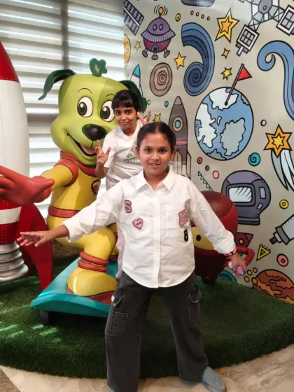 Two friends pose with our space-themed Tinga Dojo statue near the rocket ship.