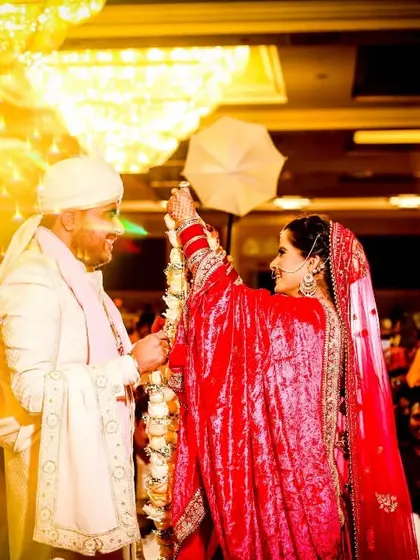 Another angle of the magical Varmala ceremony. The bride playfully holds a small umbrella, adding a touch of fun to this dramatic and beautifully lit moment.