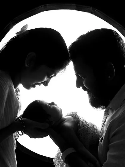 A powerful silhouette shot of new parents adoring their baby. This artistic black and white photo captures the profound love and connection in a new family.
