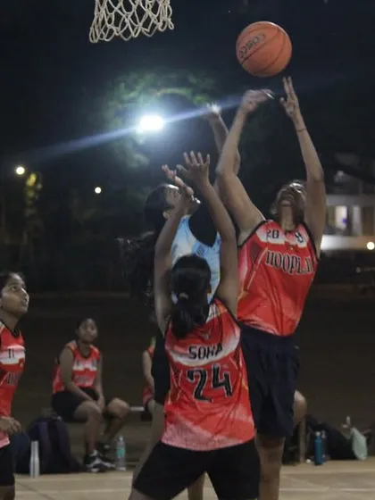 A player from the women's division goes up for a rebound against two defenders. The fight for every possession is real.