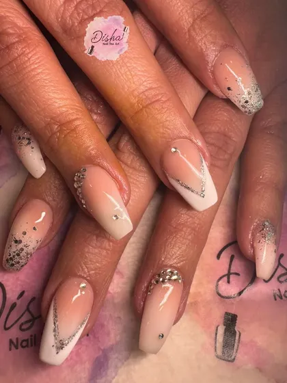 A glamorous set of baby boomer nails with silver glitter and rhinestone V-accents.