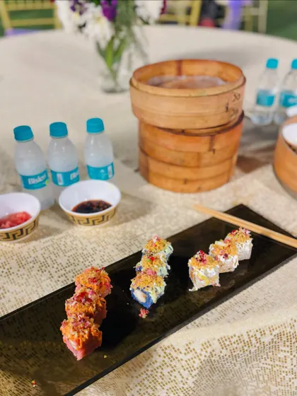 A beautifully arranged plate of sushi on a guest's table, alongside traditional bamboo steamers.