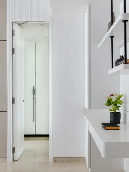 A view of the hidden door to the walk-in wardrobe, seamlessly integrated into the white fluted wall paneling.