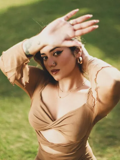 A close-up portrait where the model shields her eyes from the sun, adding a storytelling element to the fashion shoot.