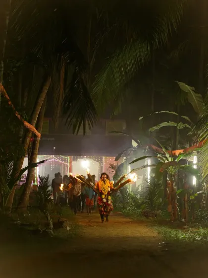 A Bhoota Kola performer makes their way through a path lined with palm trees, the torchlight creating a mystical glow. I look for these moments that blend cultural tradition with the natural beauty of the Karavali region.