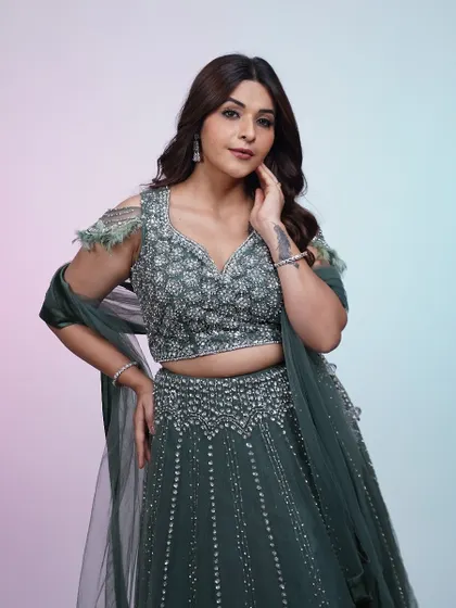 A full view of the dark green lehenga, showing the beautiful A-line silhouette and the way the dupatta is draped for an elegant look.