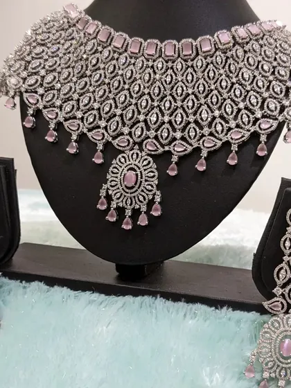 This stunning diamond-look alike AD set in pastel pink is perfect for a modern, romantic reception look. It comes with beautiful statement earrings.