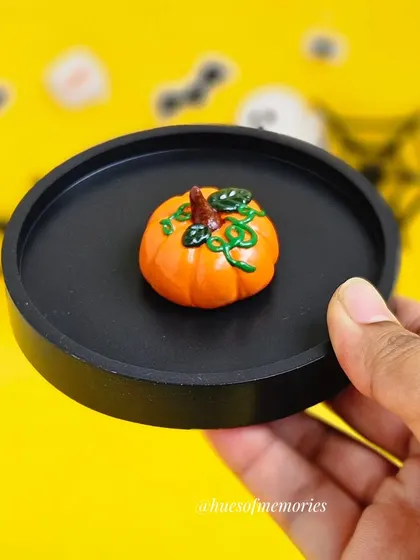 This round black trinket tray features a tiny, detailed pumpkin in the center. It's a charming and subtle addition to your Halloween decor.