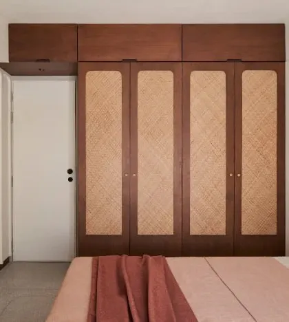 The 'dusty rose bedroom' is designed with a 'less is more' philosophy. The custom wardrobe with woven panel doors and the simple bed frame create a space that is serene and uncluttered.