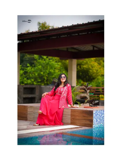 A stylish solo portrait of the bride by the pool. Her relaxed pose and chic sunglasses add a modern touch to her traditional Haldi look.