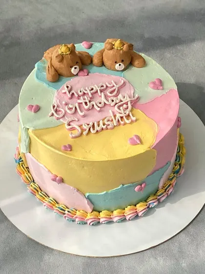A cute and colorful birthday cake with a pastel patchwork design. It's topped with two adorable teddy bears sculpted from whipped cream, a technique that requires a lot of patience but gives a lovely result.