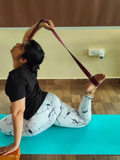 The same student demonstrating the use of props to safely explore the King Pigeon Pose, focusing on opening the hips and shoulders.