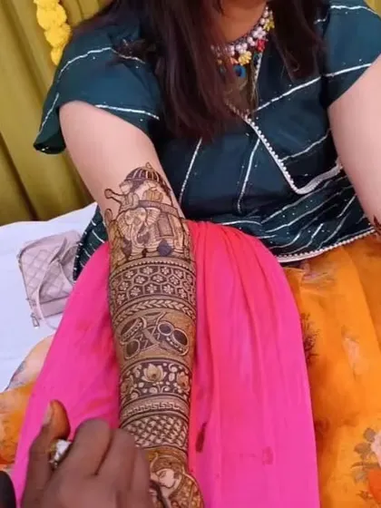 A candid shot of a client during her mehendi application, already looking happy with the progress.