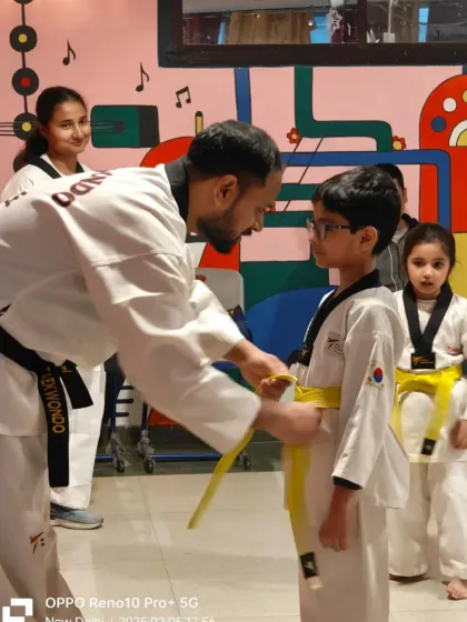 A close-up of a coach carefully tying a yellow belt on one of our youngest students. We provide individual attention to ensure everyone feels supported.