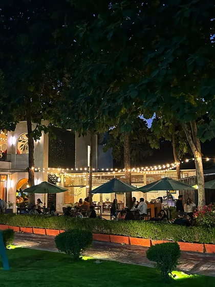 The cafe patio at night, illuminated by string lights, offers a perfect ambiance for an evening gathering.