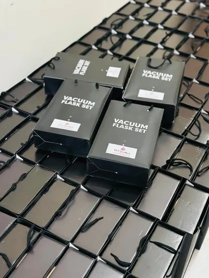 A wide shot showing the scale of a corporate order, with countless gift boxes and branded bags neatly arranged.