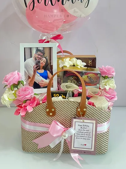Here's a closer view of the personalized birthday basket, showcasing the custom photo frame, a handwritten gift tag, and the beautiful arrangement of pink roses and treats inside the stylish jute and leather bag.