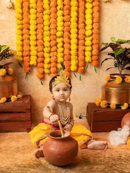 Our little Krishna is caught being mischievous with a pot of butter. These playful shots are a highlight of the Janmashtami sessions.