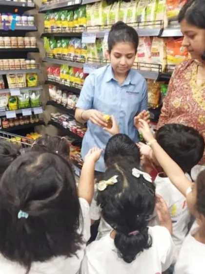 A supermarket employee shows the children a product, explaining its use. Interacting with community helpers is a valuable part of our field trips.
