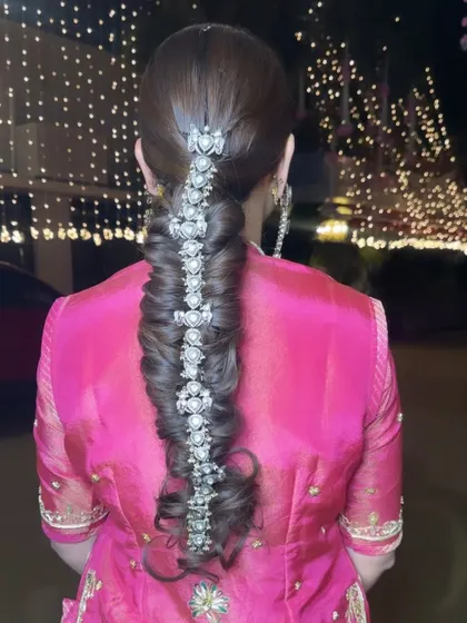 A stunning and intricate hairstyle for a special occasion. This beautiful pull-through braid is decorated with a statement silver hair accessory, creating a look that is both glamorous and unique.