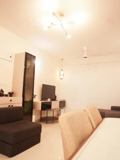 A minimalist living and dining area with a dark sofa and simple, modern lighting fixtures. The space is designed to be functional and uncluttered.