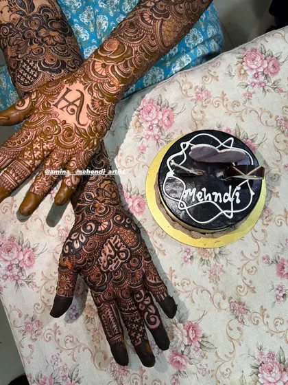 A fun shot of the personalized 'H' mehendi next to a "Mehndi" themed cake, celebrating the occasion.
