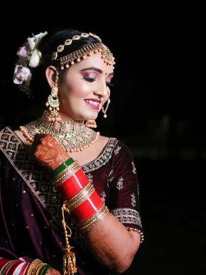 A beautiful portrait of a smiling bride, showcasing her stunning necklace, chooda, and flawless makeup.