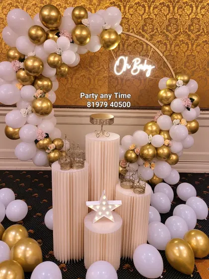 An elegant "Oh Baby" setup with a white and gold balloon arch, perfect for a sophisticated baby shower.