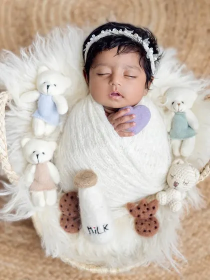 An overhead view of the milk and cookies theme, showing the baby holding a little purple heart. The textures of the fur and knit blanket add coziness.
