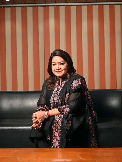 Another look for Mrs. Anuradha Prasad, this time in a more relaxed setting on a sofa. This shows a different, more contemplative side of her personality while maintaining a professional feel.