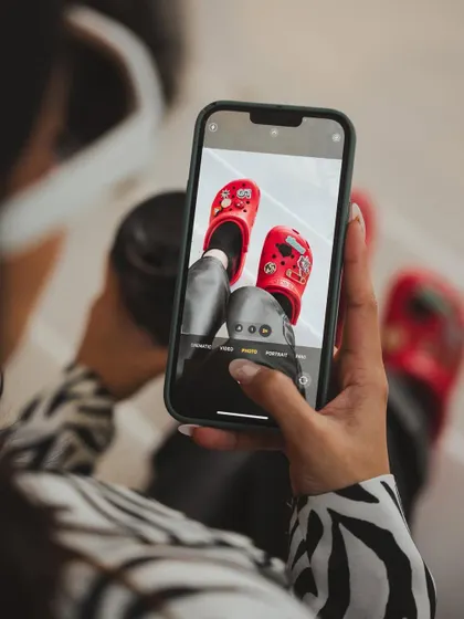 A 'photo-within-a-photo' shot for a Crocs social media campaign. This meta-narrative is modern and engaging, showing how the product is not just worn but also shared and celebrated online.