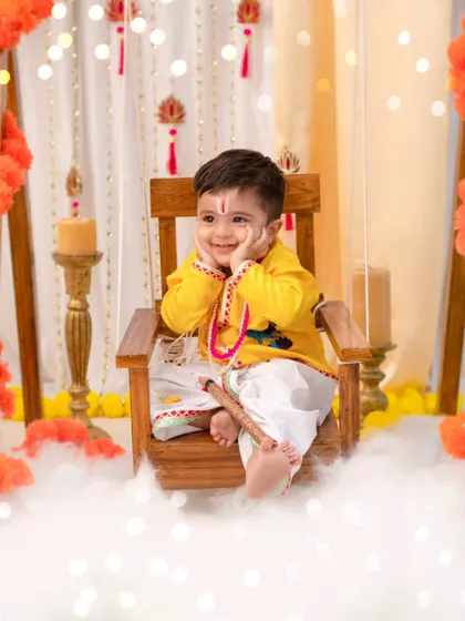 A contemplative 'Little Kanha'. Even the quiet moments are beautiful, showcasing the intricate details of the costume and the dreamy, cloud-like set.
