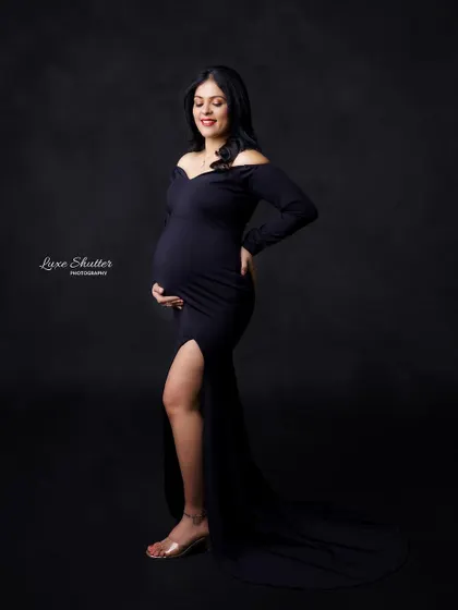 A classic off-the-shoulder black gown is always a chic and timeless choice. This side profile beautifully highlights the baby bump.