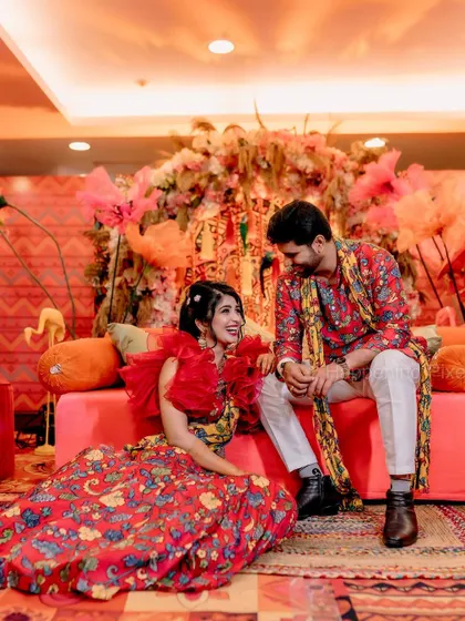 A quiet moment between the couple amidst the celebration. The rich textures and colours of the Mehendi decor, from the floral arrangements to the patterned textiles, create a warm and intimate setting.
