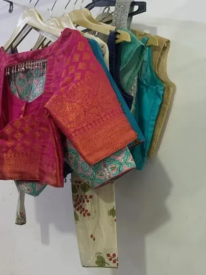 A collection of custom-stitched blouses hanging in my workshop. I can create any style you need, from traditional brocade blouses to modern sleeveless designs.