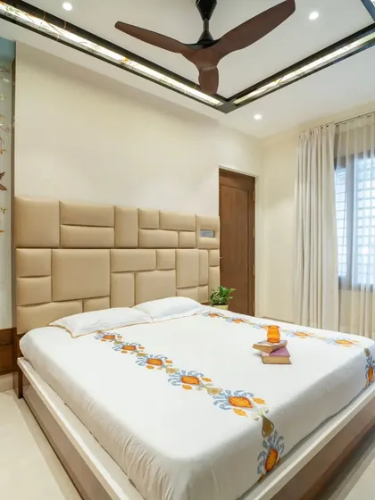 A calm and elegant bedroom design featuring a custom upholstered headboard and a beautiful etched glass partition.