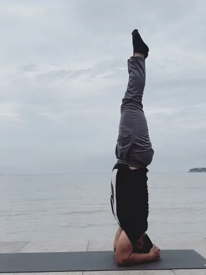 A classic headstand (Sirsasana) against the backdrop of the ocean. This inversion is known for calming the mind while strengthening the entire body.