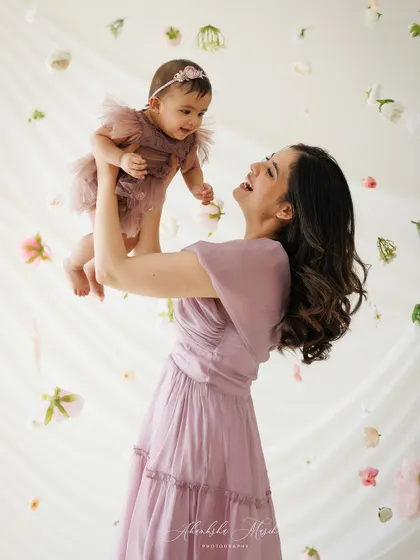 A mother's laughter fills the air as she lifts her baby. This dynamic and joyful portrait is full of life and love.