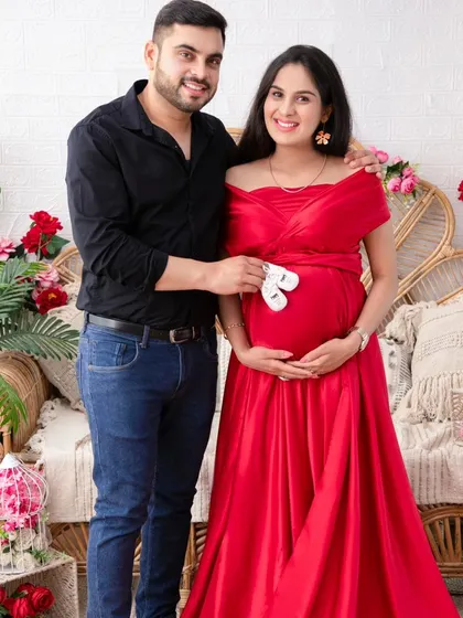 A sweet and classic pose. The couple holds a pair of tiny shoes over the baby bump, a timeless symbol of their anticipation and love.
