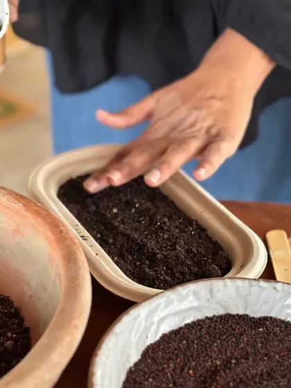 A close-up of hands patting down the soil. Our workshops are all about the hands-on experience of connecting with the earth.