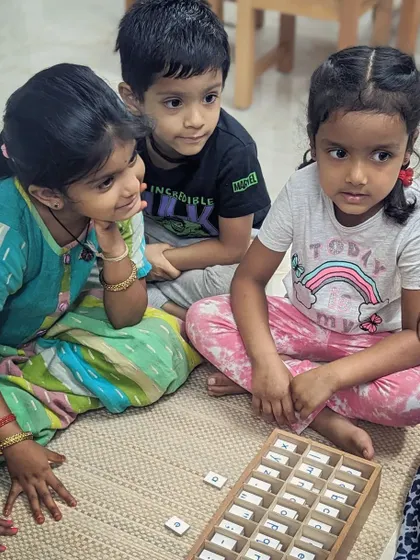 A group of children gathers around the Movable Alphabet, working together to build words. This is not a teacher-led lesson, but a spontaneous collaboration that fosters social skills, language development, and a shared sense of accomplishment.