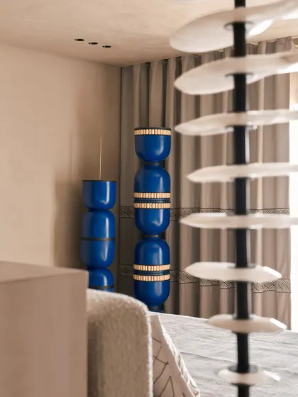 A detail shot focusing on the vibrant blue stacked vases, which serve as a striking art piece in the bedroom. This highlights our method of using bold accents to punctuate an otherwise neutral and calming space.