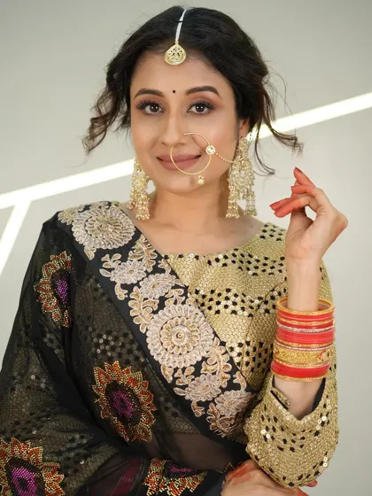 A close-up of a model in a traditional look, featuring a black and gold embroidered saree and a nath.