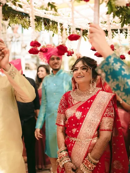 The bride's brothers hold the phoolon ki chadar over her as she makes her entrance.