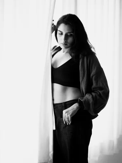This black and white portrait has a high-contrast, film noir feel. The light from the window acts as a natural frame, drawing the viewer's eye.