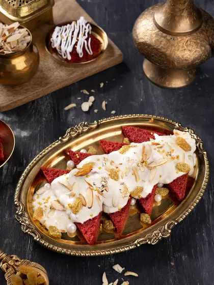 A wider view of the Red Velvet Shahi Tukda, showing the intricate plating and surrounding brassware that adds to its royal vibe.