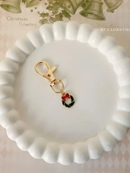 A classic Christmas wreath charm with a little red bow. It's a timeless and elegant festive accessory.