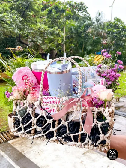 This stunning macrame basket is filled with goodies for both mom and baby, including personalized sippers, a baby bib, and fresh flowers, making it a perfect baby shower gift.