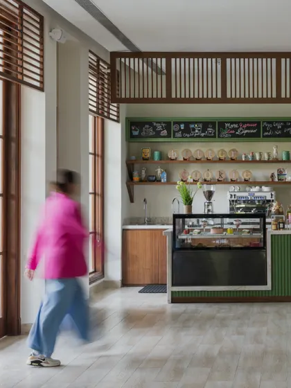The cafe and bakery corner at the DLF Club restaurant. The design uses natural wood, a playful chalkboard menu, and warm lighting to create a charming and welcoming spot for a casual coffee or pastry.