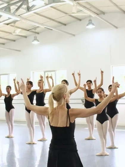 Ms. Yana leads the class in the new choreography, her arms outstretched as she guides the students through the unfamiliar but exciting movements.